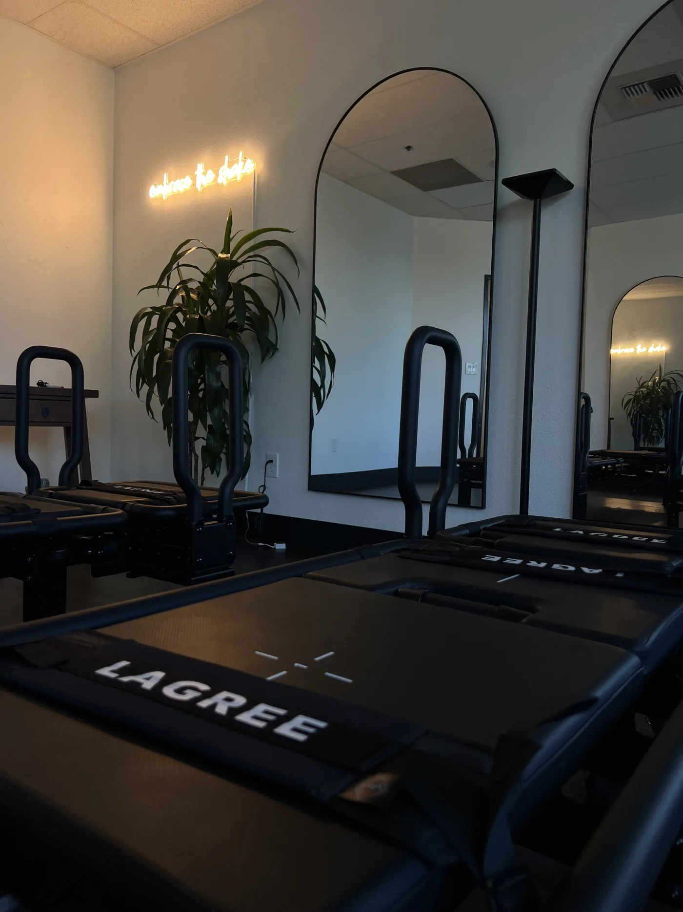 The Lagree reformer room at Sacred Studios in Roseville — Megaformers, arched mirrors, and neon accent