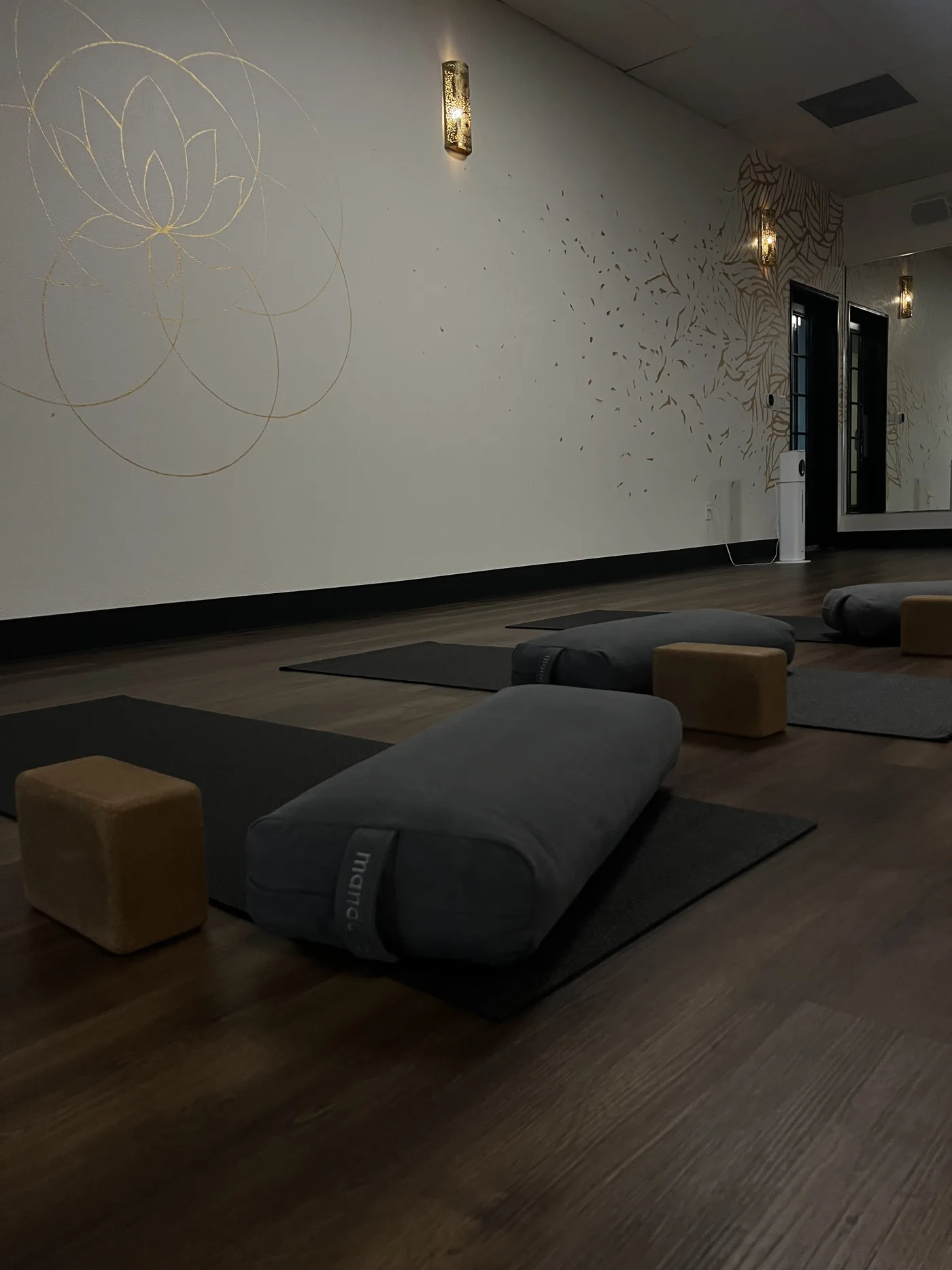 The yoga room at Sacred Studios, mats and bolsters set beneath the gold lotus mural